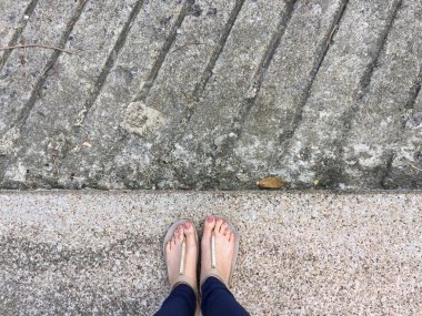 Ayakları ile kahverengi altın sandalet ve mavi pantolon zemin zemin üzerine kadın ayakları üzerinde çivi kadar kapatın