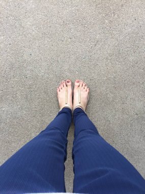 Ayakları ile kahverengi altın sandalet ve mavi pantolon zemin zemin üzerine kadın ayakları üzerinde çivi kadar kapatın