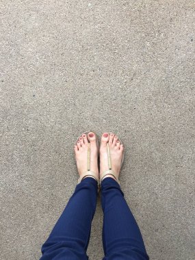 Ayakları ile kahverengi altın sandalet ve mavi pantolon zemin zemin üzerine kadın ayakları üzerinde çivi kadar kapatın