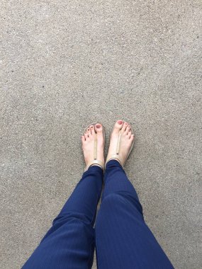 Ayakları ile kahverengi altın sandalet ve mavi pantolon zemin zemin üzerine kadın ayakları üzerinde çivi kadar kapatın