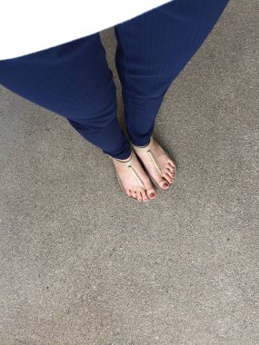 Ayakları ile kahverengi altın sandalet ve mavi pantolon zemin zemin üzerine kadın ayakları üzerinde çivi kadar kapatın