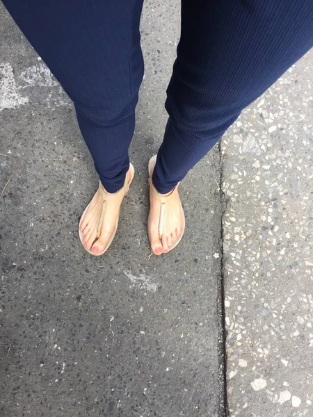 Ayakları ile kahverengi altın sandalet ve mavi pantolon zemin zemin üzerine kadın ayakları üzerinde çivi kadar kapatın — Stok fotoğraf