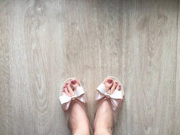 Kadın ayaklar ve bacaklar bir ahşap zemin üzerinde pembe terlik pedikür ile — Stok fotoğraf