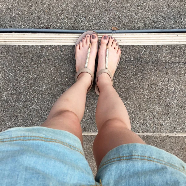 Jeune fille pieds avec des ongles bruns dans des sandales en or sur fond d'escalier — Photo