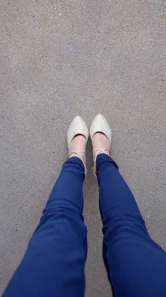 Женщина ноги на высоком каблуке золотые сандалии стоять на земле, на открытом фоне — стоковое фото