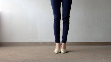 Kadın bacaklar yüksek topuk altın sandalet Stand yerde, açık arka plan