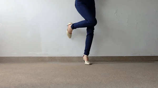 Kobieta nogi w wysokiej pięty złote sandały stoją na ziemi, odkryty tło — Zdjęcie stockowe