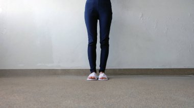 Genç kadın bacaklar ve ayaklar yere, kapalı arka plan beyaz terlik ve Mavi pantolon giyiyor