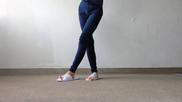 Young Females Legs and Feet Wearing White Slippers and Blue Pants on Ground, Indoor Background — Stock Photo, Image