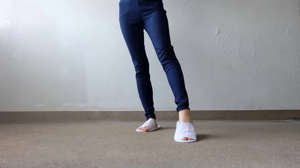 Young Females Legs and Feet Wearing White Slippers and Blue Pants on Ground, Indoor Background — Stock Photo, Image