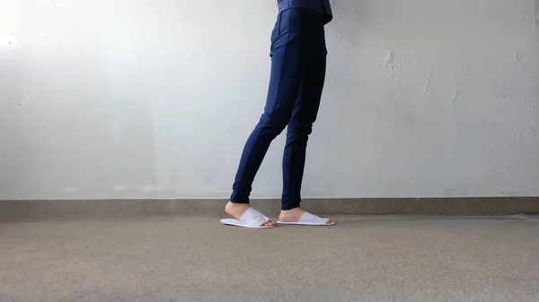 Young Females Legs and Feet Wearing White Slippers and Blue Pants on Ground, Indoor Background — Stock Photo, Image