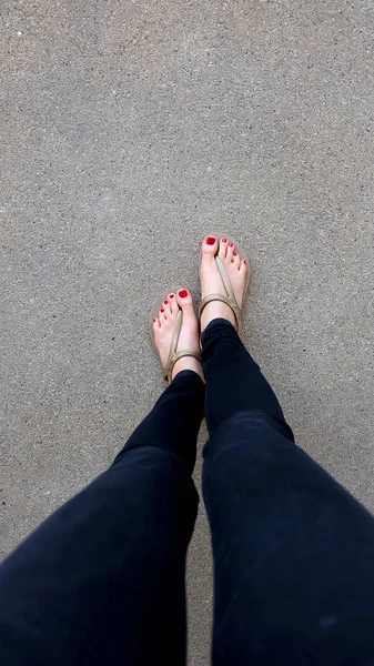 Close Up on Girl 's Feet Wearing Golden Sandals on Ground Background — стоковое фото