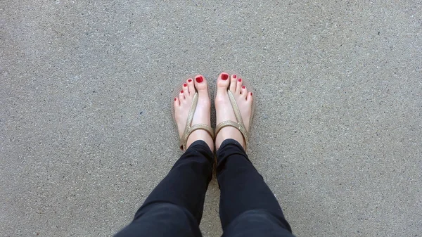 Gros plan sur les pieds de la fille portant des sandales dorées sur fond de sol — Photo