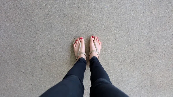 Gros plan sur les pieds de la fille portant des sandales dorées sur fond de sol — Photo