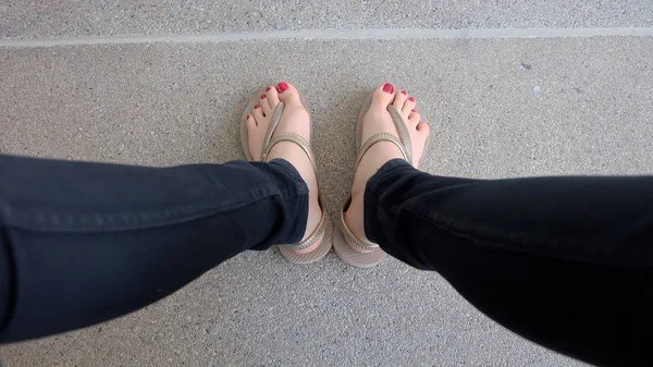 Gros plan sur les pieds de la fille portant des sandales dorées sur fond de sol — Photo