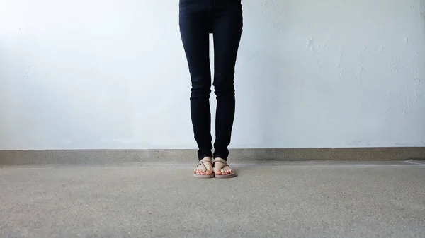 Gros plan sur les pieds de la fille portant des sandales dorées sur fond de sol — Photo