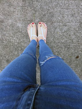 Kırmızı tırnak sandalet ve Mavi Jeans kadın beton zemin geçmiş üstünde çıplak ayakla, yakın çekim