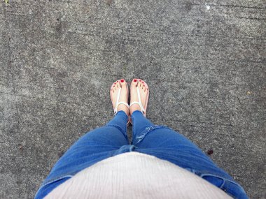Kırmızı tırnak sandalet ve Mavi Jeans kadın beton zemin geçmiş üstünde çıplak ayakla, yakın çekim