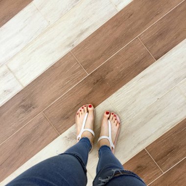 Kırmızı tırnak sandalet ve Mavi Jeans kadın üzerinde döşeme arka planı çıplak ayakla, yakın çekim