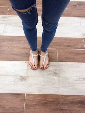 Kırmızı tırnak sandalet ve Mavi Jeans kadın üzerinde döşeme arka planı çıplak ayakla, yakın çekim