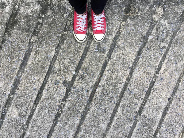 Closeup fotografii z žena nosí červené tenisky na pozadí betonové podlahy — Stock fotografie