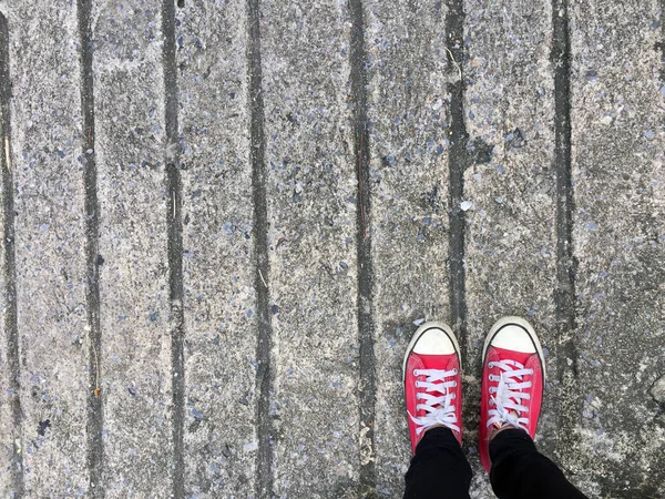 Foto de primer plano de una mujer que usa zapatillas rojas en el fondo de hormigón —  Fotos de Stock