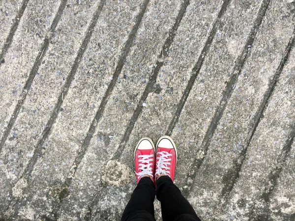 Closeup foto van van vrouw dragen rode Sneakers op de betonnen vloer-achtergrond — Stockfoto