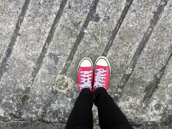 Foto di primo piano della donna che indossa scarpe da ginnastica rosse sullo sfondo del pavimento in cemento — Foto Stock