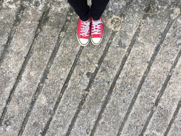 Closeup fotografii z žena nosí červené tenisky na pozadí betonové podlahy — Stock fotografie