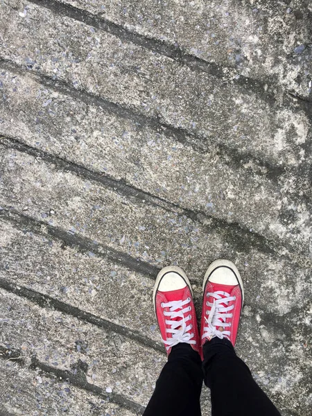 Foto de primer plano de una mujer que usa zapatillas rojas en el fondo de hormigón — Foto de Stock