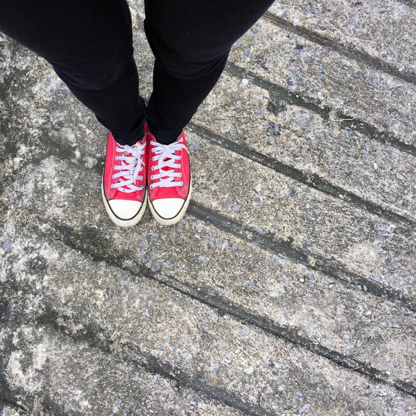 Foto de primer plano de una mujer que usa zapatillas rojas en el fondo de hormigón —  Fotos de Stock