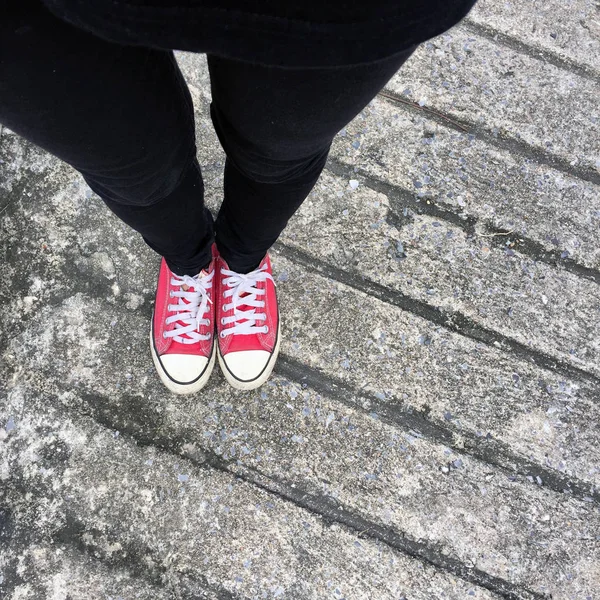 Foto de primer plano de una mujer que usa zapatillas rojas en el fondo de hormigón —  Fotos de Stock