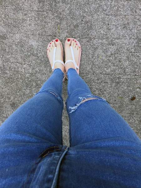 Kırmızı tırnak sandalet ve Mavi Jeans kadın beton zemin geçmiş üstünde çıplak ayakla, yakın çekim