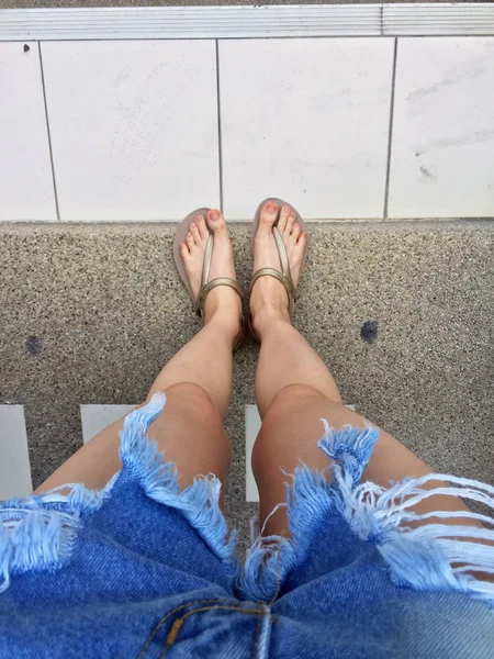 De cerca en los pies de la muchacha con sandalias de oro y pantalones vaqueros azules en la calle — Foto de Stock