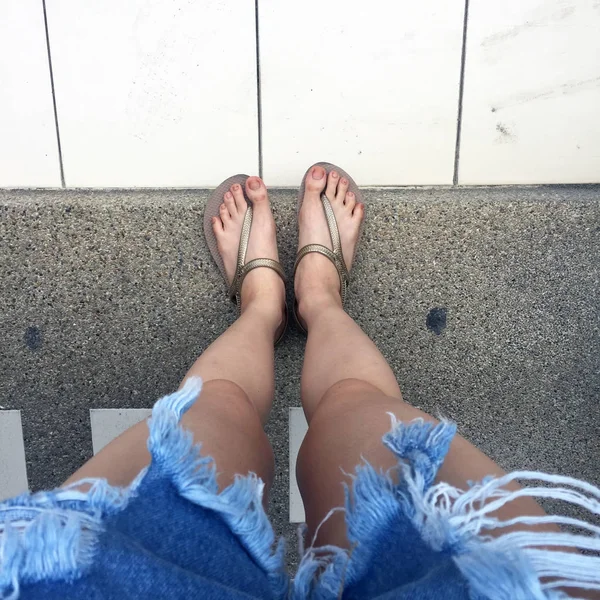 Close Up on Girl 's Feet vestindo sandálias de ouro e jeans azuis na rua — Fotografia de Stock
