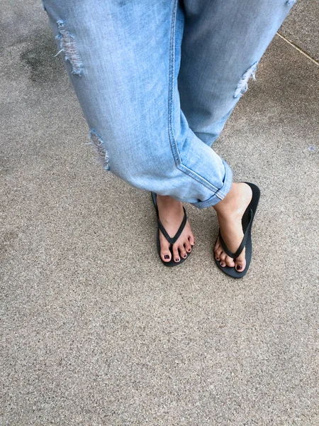 Close Up on Girl's Feet Wearing Black Sandals and Blue Jeans on the Street — Stock Photo, Image