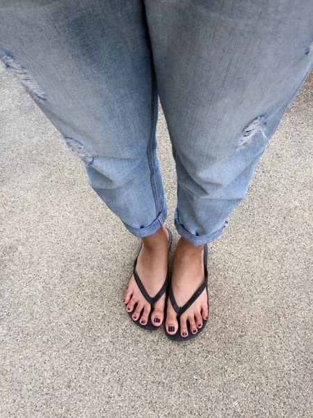 Gros plan sur les pieds des filles portant des sandales noires et des jeans bleus dans la rue — Photo