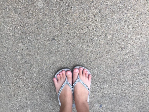 Kvinnliga fötter bär grå Sandal på gatan — Stockfoto