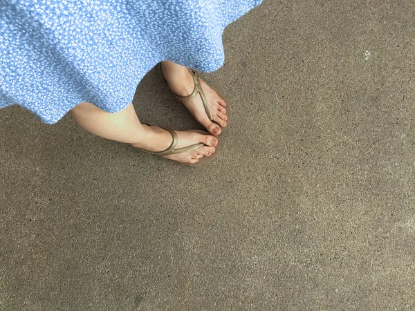 Pies femeninos desgaste sandalias y vestido azul en la calle — Foto de Stock
