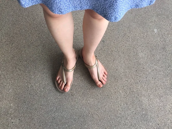Pés femininos usam sandálias e vestido azul na rua — Fotografia de Stock