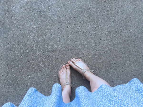 Vrouwelijke voeten dragen sandalen en blauwe jurk op straat — Stockfoto