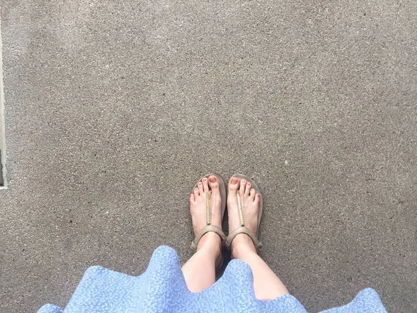 Vrouwelijke voeten dragen sandalen en blauwe jurk op straat — Stockfoto