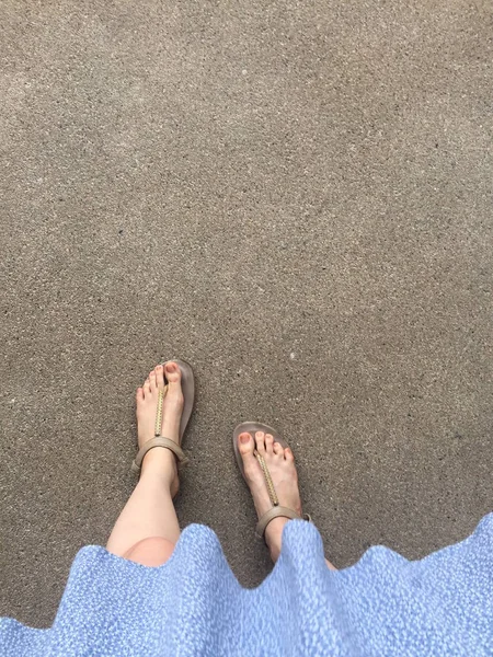 Pés femininos usam sandálias e vestido azul na rua — Fotografia de Stock