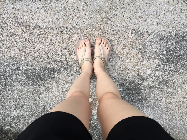 Pieds féminins en sandales dorées et pantalons noirs sur la rue — Photo