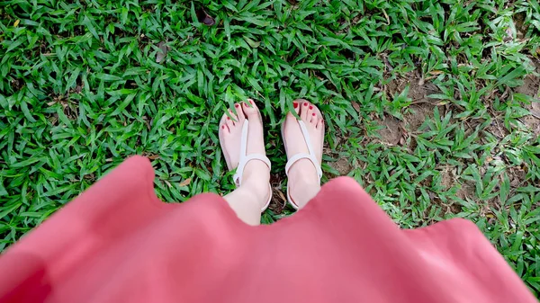 Close-up op meisje voeten dragen sandalen op groen gras — Stockfoto