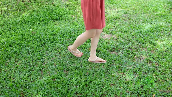 Κοντινό πλάνο στα πόδια του κοριτσιού που φοράει σανδάλια για την πράσινη χλόη — Φωτογραφία Αρχείου