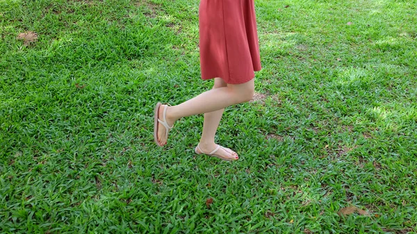 在绿色草地上穿着凉鞋的女孩的脚上特写 — 图库照片
