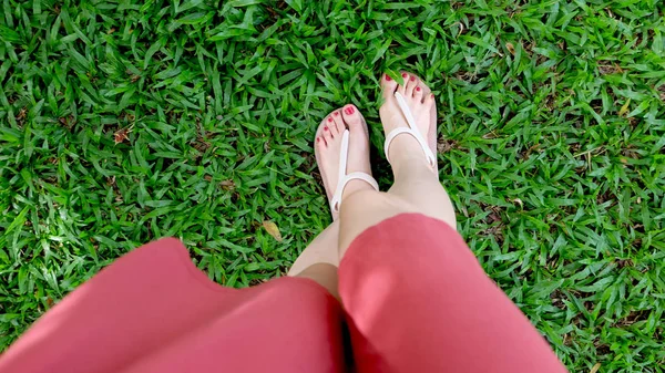 De cerca en los pies de la muchacha con sandalias sobre hierba verde —  Fotos de Stock