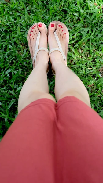 De cerca en los pies de la muchacha con sandalias sobre hierba verde —  Fotos de Stock