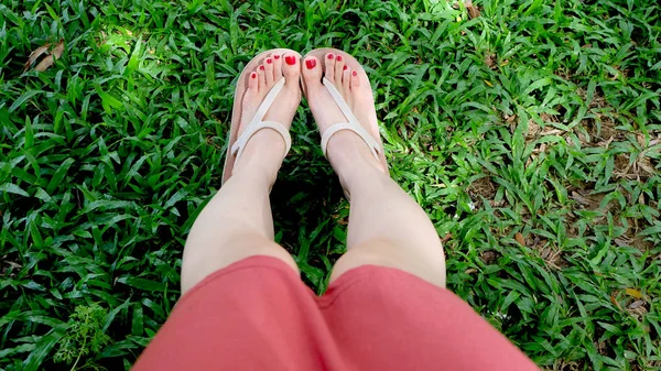 Close-up op meisje voeten dragen sandalen op groen gras — Stockfoto